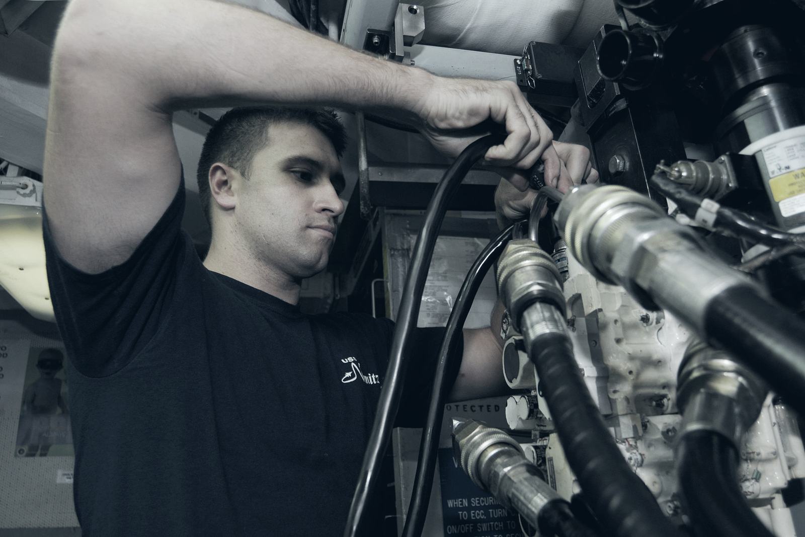 Technician working on aircraft hydraulic lines and accessories